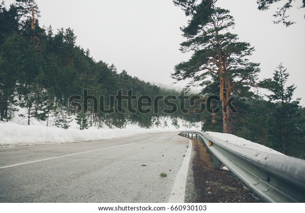 High mountain road. Mountain landscape\
with snow. Road trip trough the mountains. Road in the forest. View\
of a mountain road in Navacerrada. \
