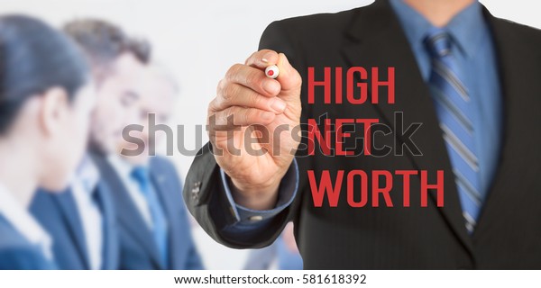High Net Worth, Male hand in business wear\
holding a thick pen writing, with office team blurred in\
background, digital\
composing.