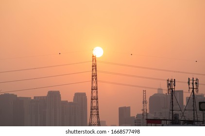 High power electricity pole in urban areas with sun at sunset. Energy supply