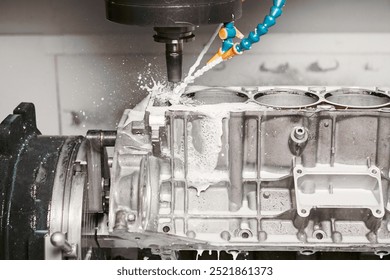 High precision cnc milling machine makes holes in the car engine with a coolant. 