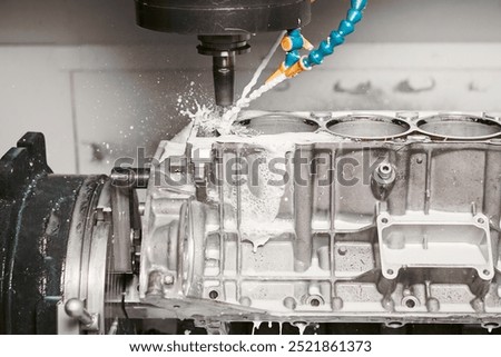 High precision cnc milling machine makes holes in the car engine with a coolant. 