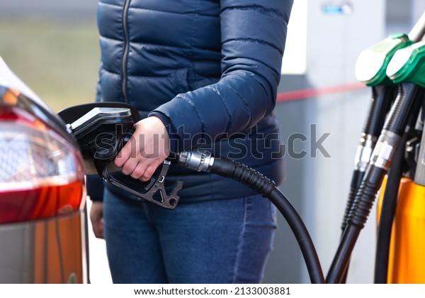 High\
prices of petrol and diesel fuel ath the petrol station, young\
woman refueling the car, economic crisis\
concept