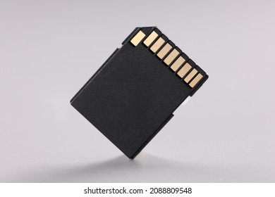 High quality black sd memory card with small gold disc on gray background