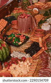 High quality, interesting serving of various food, both sweet and salty, including cheese, peanuts, cucumber, tomato, cookies, olives, salami,...