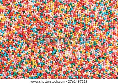High resolution background thousands tiny, multi colored sugar nonpareils, creating vibrant and chaotic rainbow texture