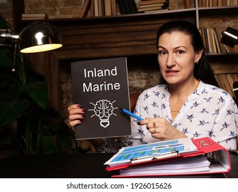 High Resolution Business Woman Holding Black Notepad With Written Text Inland Marine - Closeup Shot.
