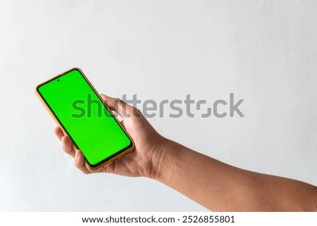 High resolution image capturing a pair of hands holding a modern smartphone with a blank green screen, isolated on a clean white background.