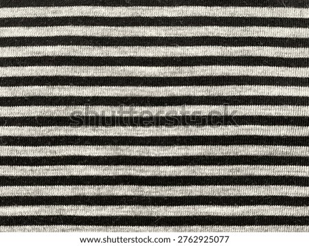 A high resolution, top down shot of a soft cotton fabric featuring a consistent horizontal striped pattern in black and heather grey melange. The detailed weave of the textile provides a realistic and organic feel. This classic monochrome aesthetic is perfect for fashion backgrounds, lifestyle content, minimalist web design, or as a texture overlay for creative projects