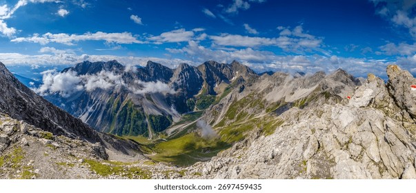 High resolution widescreen panorama of mountain landscape. Panorama of Alps mountains on a sunny day.  Blue sky with some clouds above beautiful summits alpine range of Lechtaler Austria Alps