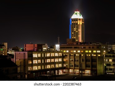 High Rise Building Towers Over Lit Multi-story School At Night