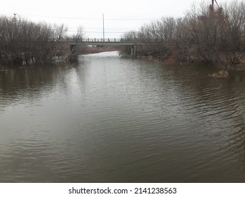 High River Water Close To A Bridge On A Grey Day