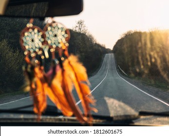 High road through windshield of car with blurred dreamcatcher at sunset. Road trip background - Powered by Shutterstock