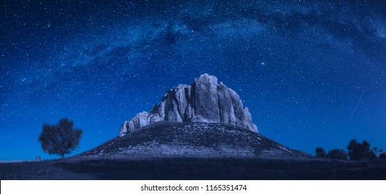 High Rocky Mountain Peak In A Valley Against Milky Way In A Night Starry Sky. 