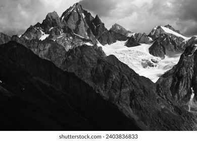 High rocky mountains with glacier in storm clouds before rain. Caucasus Mountains. Georgia, region Svanetia at summer. Remote location. Black and white toned landscape. High contrast. - Powered by Shutterstock