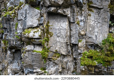 High rocky stone wall with green moss