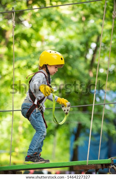 High ropes walk. Balance beam and rope\
bridges. Happy Little child climbing a tree. Cute child boy.\
Children summer activities.\
Playground.