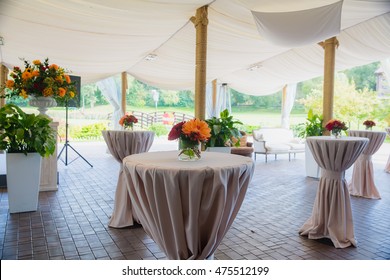 High Round Tables Beautified With Red Bouquets Stand Under A White Pavilion