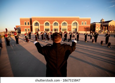 A High School Band Warms Up In A Parking Lot Before Their Performance.