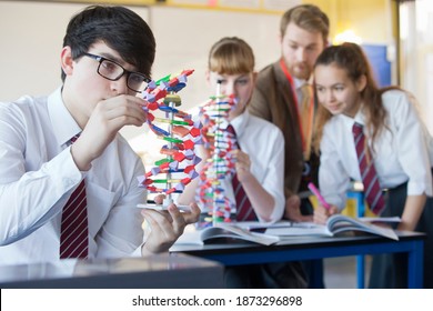 High school boy assembling a helix DNA model in a science class with her classmates and professor in the background. - Powered by Shutterstock