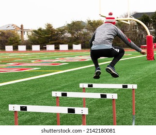 A High School Boy Finishing Jumping Over A Few Track Hurdles At Practice.