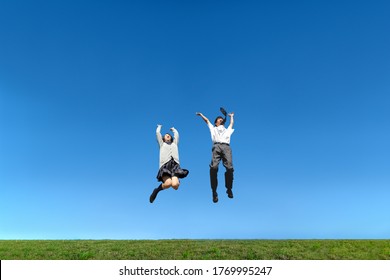 High School Boy And Girl Jumping Against The Blue Sky