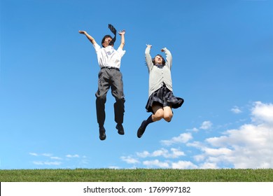 High School Boy And Girl Jumping Against The Blue Sky