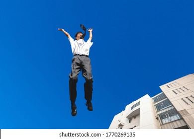 High School Boy Jumping Against The Blue Sky