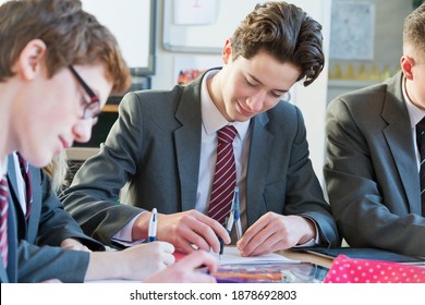 High School Boy Sitting With His Classmates And Using A Drawing Compass.