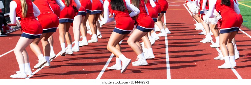 High School Cheelearders Dancing On The Track Perfoming For The Fans At A Football Game.