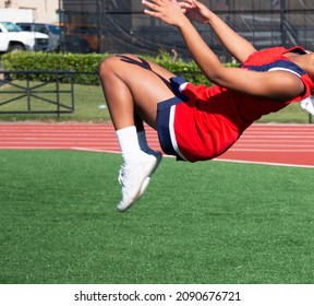 A High School Cheerleader In A Red Whte And Blue Uniform Is Practicing Her Tumbling Flips Before Her Homecoming Performance.