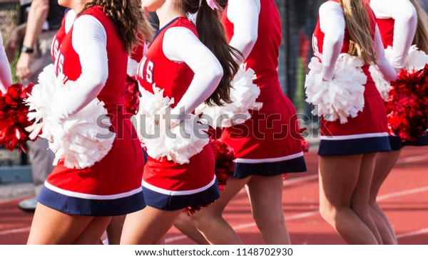 High school cheerleaders are cheering during a\
football game.