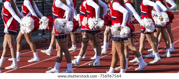 High school cheerleaders\
cheering on the crowd at a football game on a sunny afternoon in\
the fall.