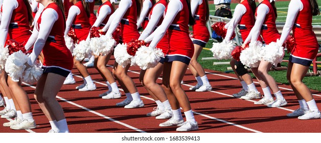 High School Cheerleaders In Red And White Unifors Perforiming For The Crowd During Homecoming Football Game.