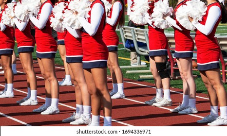 High School Cheerleaders In Red And White Uniforms Cheer For The Fans At A High School Football Game.