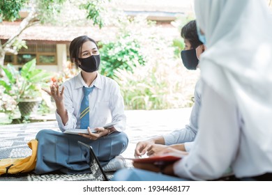 High School Children Wearing Masks Holding Books While Studying Outdoor Groups