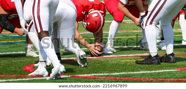 A high school football long snapper\
is ready to snap the ball to the punter during a\
game.