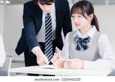 A high school girl asking a question to her teacher in the classroom - Shutterstock ID 2265461233