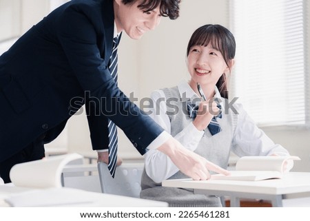 A high school girl asking a question to her teacher in the classroom