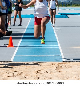 A High School Girl Is Competiting In The Triple Jump During A Track Meet Outdoors.