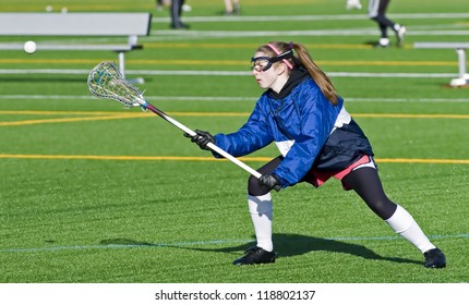 High School Girl Lacrosse Player Reaches Out To Catch The Ball.