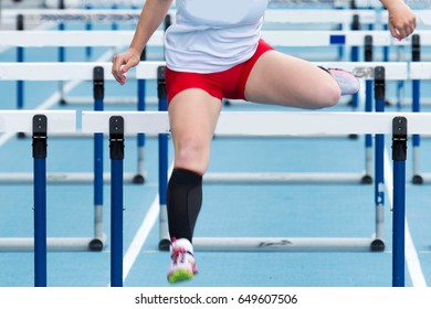 High School Girl Racing The Hurdles At A Track And Field Competition