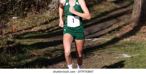 A High School Girl Is Running In A Path In The Woods During A Cross Country Race In A Park.