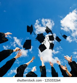 High School Graduates Tossing Up Hats Over Blue Sky.