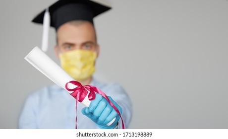 High School Graduation During A Quarantine. Student Graduate In A Hat And A Protective Mask Holds A Diploma