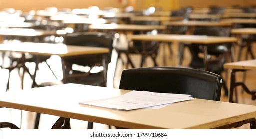 A high school hall or room set up ready for an end of year final exam to be sat by students. examination paper sitting on the edge of a desk or table.  - Shutterstock ID 1799710684
