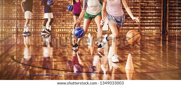 High school kids practicing football using\
cones for dribbling drill in the\
court
