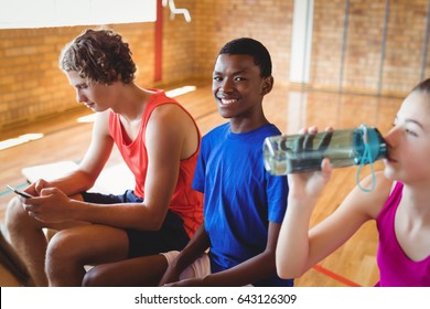 High School Kids Relaxing On Bench In Basketball Court