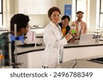 In high school laboratory, teacher demonstrating experiment with beaker to students. Education, science, teaching, chemistry, learning, classroom