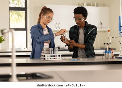 In high school laboratory, teenagers conducting science experiment with beakers and test tubes. Education, students, chemistry, teamwork, STEM, learning - Powered by Shutterstock