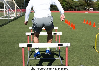 A High School Male Athlete Jumps Over Hurdles During Strength Training At Track And Field Practice